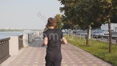 清晨，穿着黑色T恤和运动短裤的年轻运动员沿着长廊奔跑。 一个身材魁梧的男人